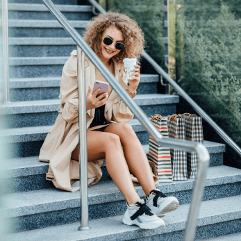businesswoman-sun-glasses-is-holding-shopping-bags-phone-smiling-after-walking-down-street 1